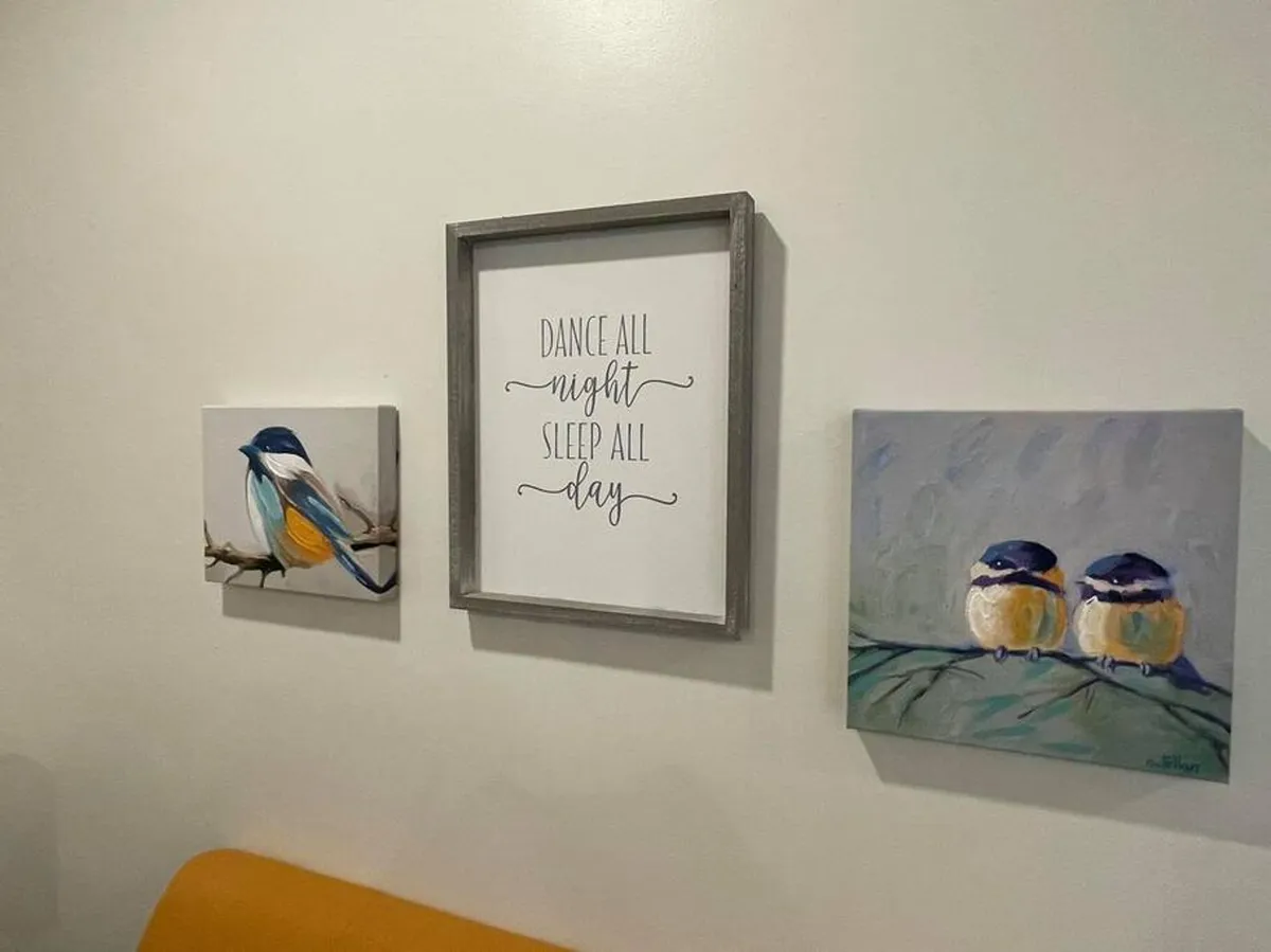 A warmly lit interior gathering space with cozy seating, framed inspirational quotes, and bird-themed paintings on the walls. The room exudes a welcoming, uplifting ambiance, ideal for small groups or families to relax together after a day of exploring. Subtle cues suggest communal moments and a lively, social environment.